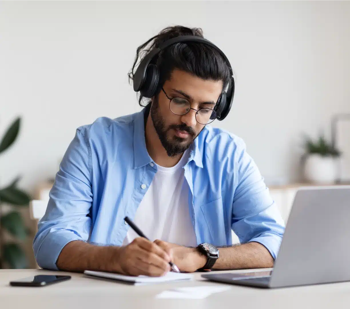 Man wearing headphones taking notes at laptop during an online dog trainer education course